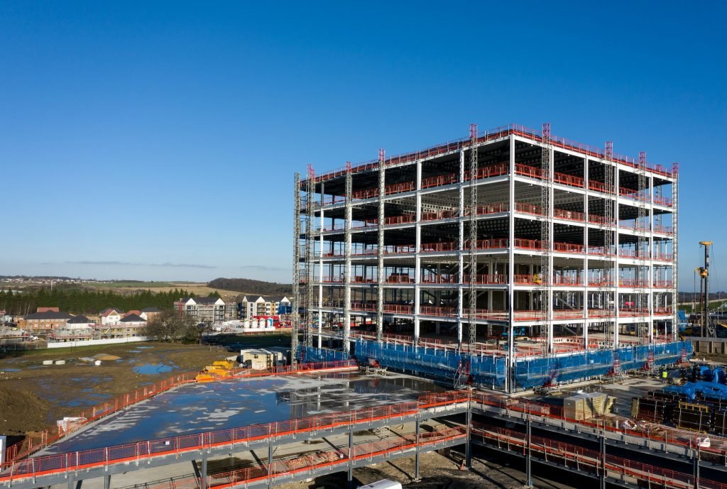 The framework of a tall building being constructed on a construction site with scaffold